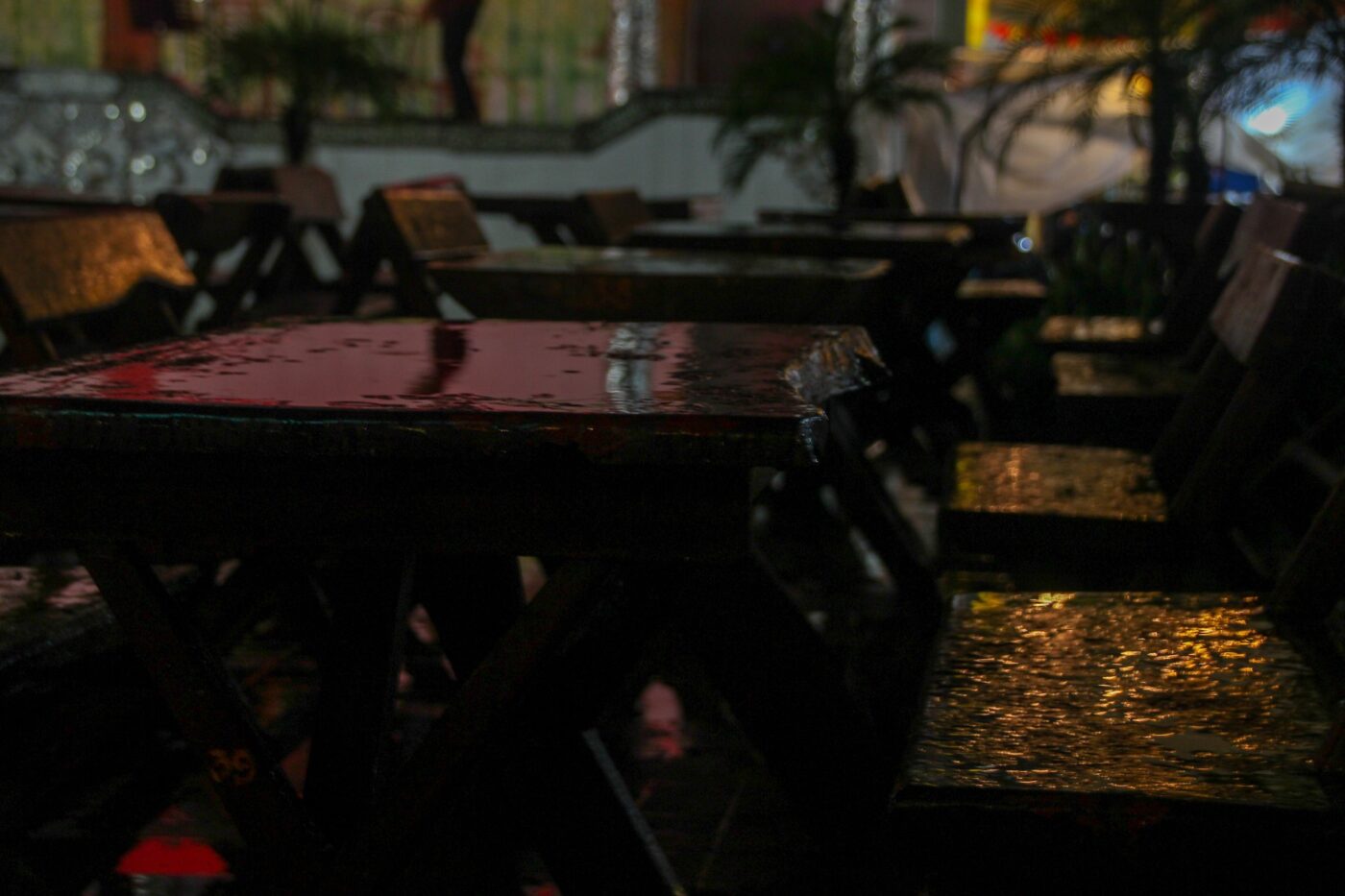 Wet wooden tables and chairs in an outdoor restaurant at night after rain – nbcreations