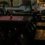 Wet wooden tables and chairs in an outdoor restaurant at night after rain – nbcreations