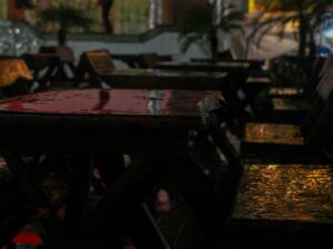 Wet wooden tables and chairs in an outdoor restaurant at night after rain – nbcreations