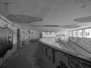 Graffiti-lined corridor in a deserted building, windows overlooking an abandoned complex – nbcreations