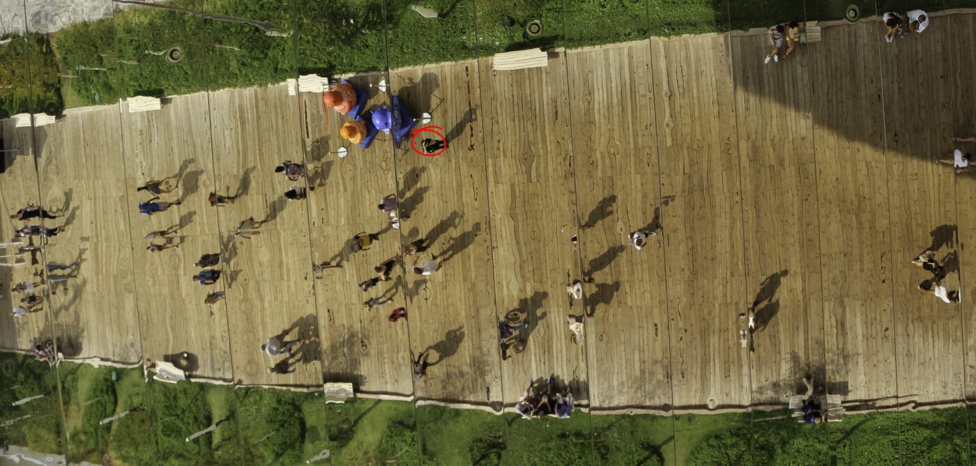 Reflection of people walking on a wooden deck, distorted by a giant mirror – nbcreations