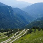 Winding road with switchbacks seen from Col de Tende, surrounded by forested mountain slopes – panoramic Alpine view - nbcreations
