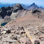 Rocky mountain ridge with a deep blue alpine lake below, surrounded by jagged peaks under a clear sky – Corsican high-altitude landscape - nbcreations