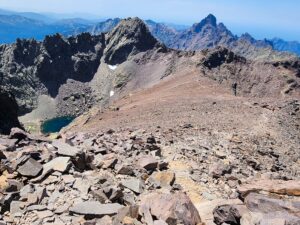Rocky mountain ridge with a deep blue alpine lake below, surrounded by jagged peaks under a clear sky – Corsican high-altitude landscape - nbcreations