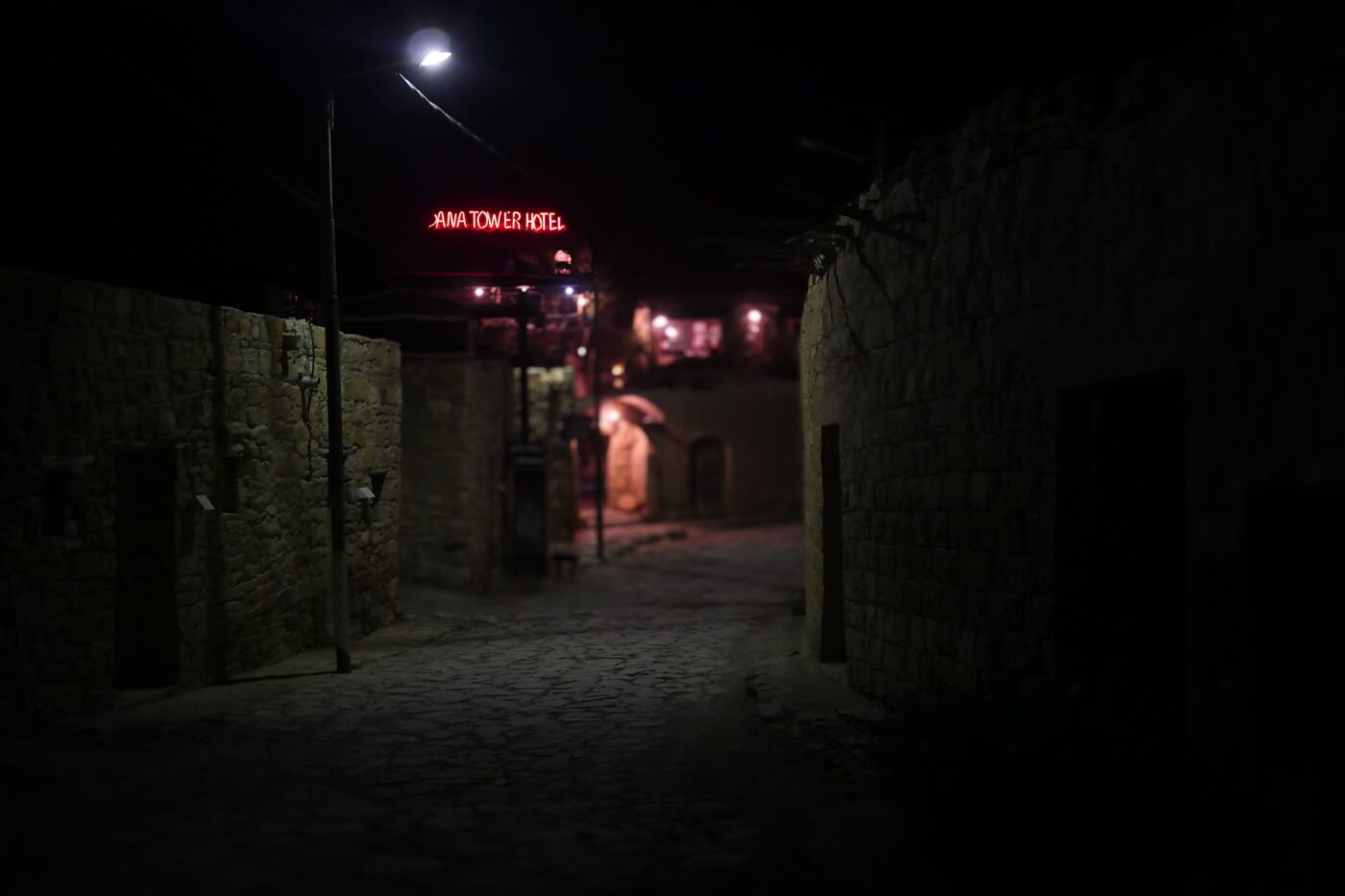 Nighttime view of a stone-paved alley in Dana village with illuminated Dana Tower Hotel sign in the background – authentic Middle Eastern night scene - nbcreations