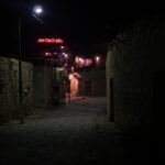 Nighttime view of a stone-paved alley in Dana village with illuminated Dana Tower Hotel sign in the background – authentic Middle Eastern night scene - nbcreations