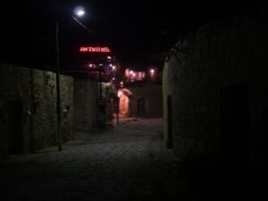 Nighttime view of a stone-paved alley in Dana village with illuminated Dana Tower Hotel sign in the background – authentic Middle Eastern night scene - nbcreations
