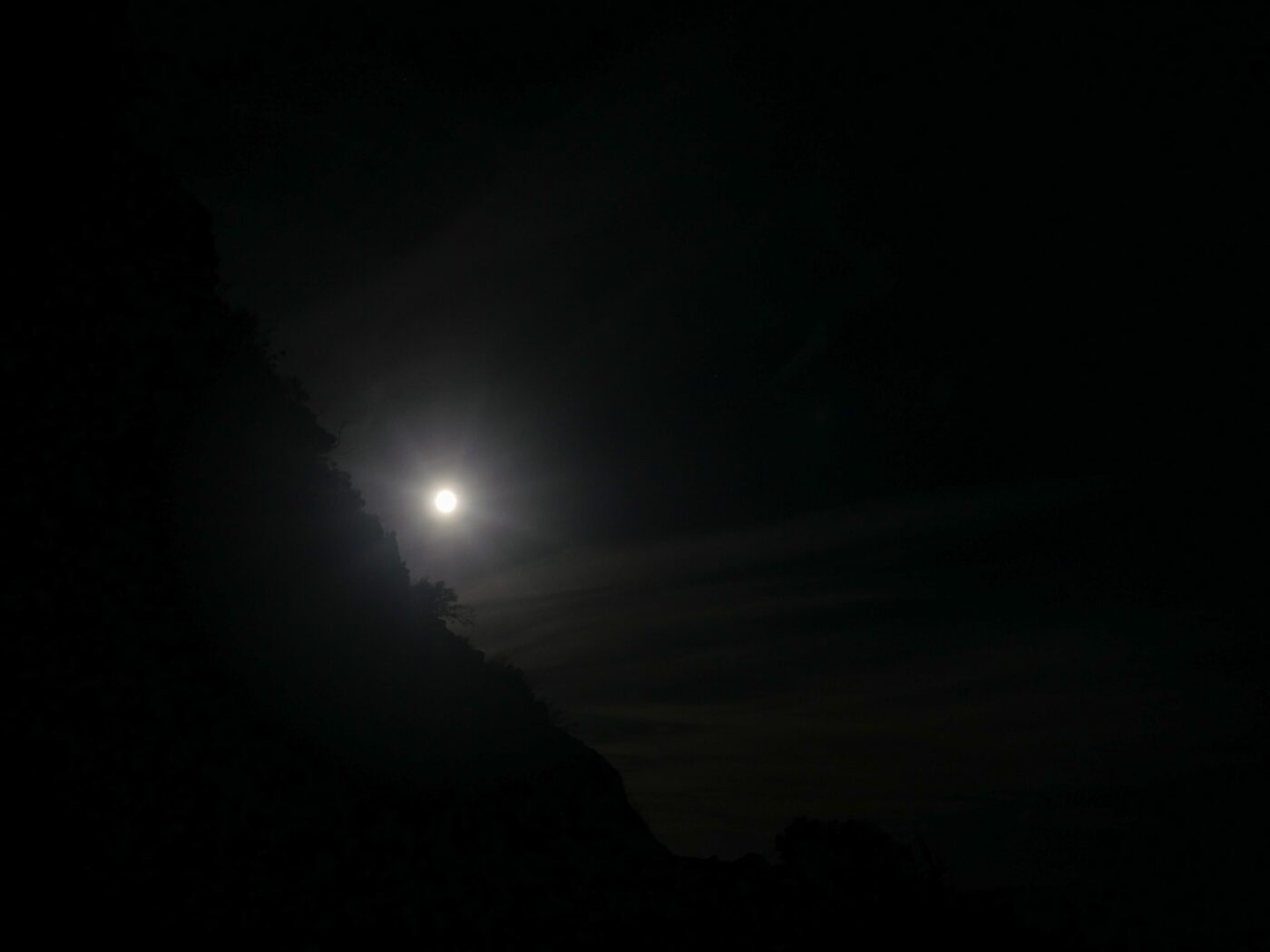 Glow of moonlight hidden behind a rocky coastline at night – luminous coastal silhouette - nbcreations