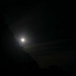 Glow of moonlight hidden behind a rocky coastline at night – luminous coastal silhouette - nbcreations