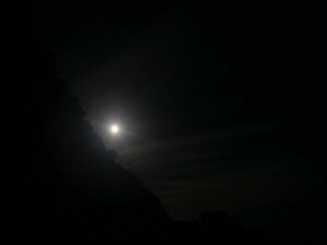 Glow of moonlight hidden behind a rocky coastline at night – luminous coastal silhouette - nbcreations
