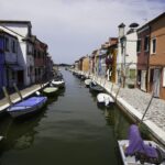 Canal in Murano lined with colorful houses and moored boats – Venetian island scene - nbcreations