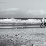 Two girls walking with a bicycle on the beach – relaxed seaside stroll - nbcreations