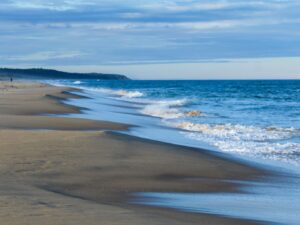 Sandy beach with a distant solitary walker on the horizon – minimal coastal scene - nbcreations