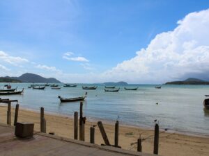 Thai beach with boats floating on the sea – tropical coastline in Thailand - nbcreations