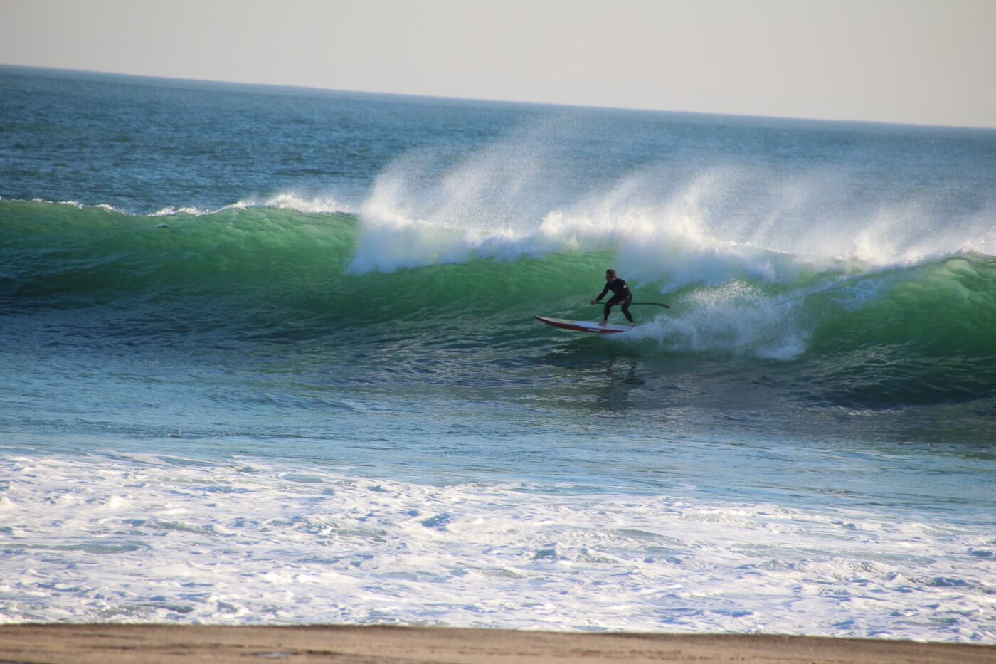 Person riding a paddleboard as a surfboard on the waves – dynamic beach activity - nbcreations