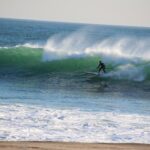 Person riding a paddleboard as a surfboard on the waves – dynamic beach activity - nbcreations