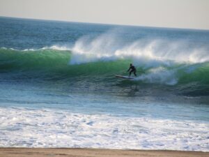 Person riding a paddleboard as a surfboard on the waves – dynamic beach activity - nbcreations