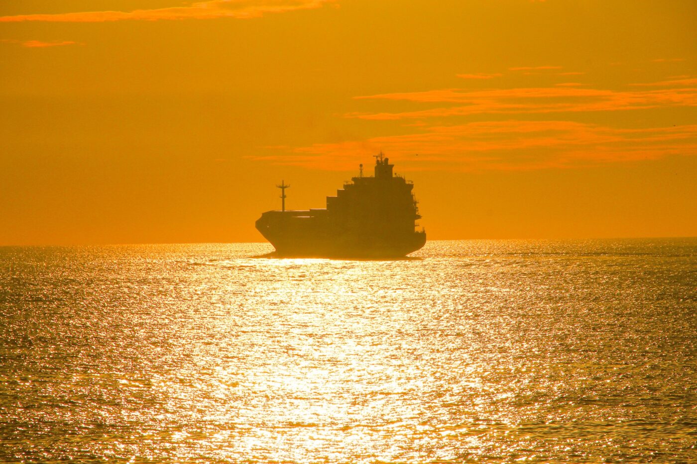Cargo ship silhouette on golden sea at sunset – nbcreations