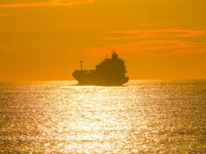 Cargo ship silhouette on golden sea at sunset – nbcreations