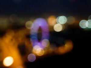 Abstract bokeh effect with colored lights and a blurred ferris wheel at night.- nbcreations