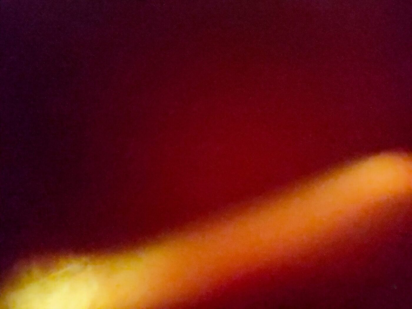 Abstract image with a yellow-orange streak on a dark red background.- nbcreations