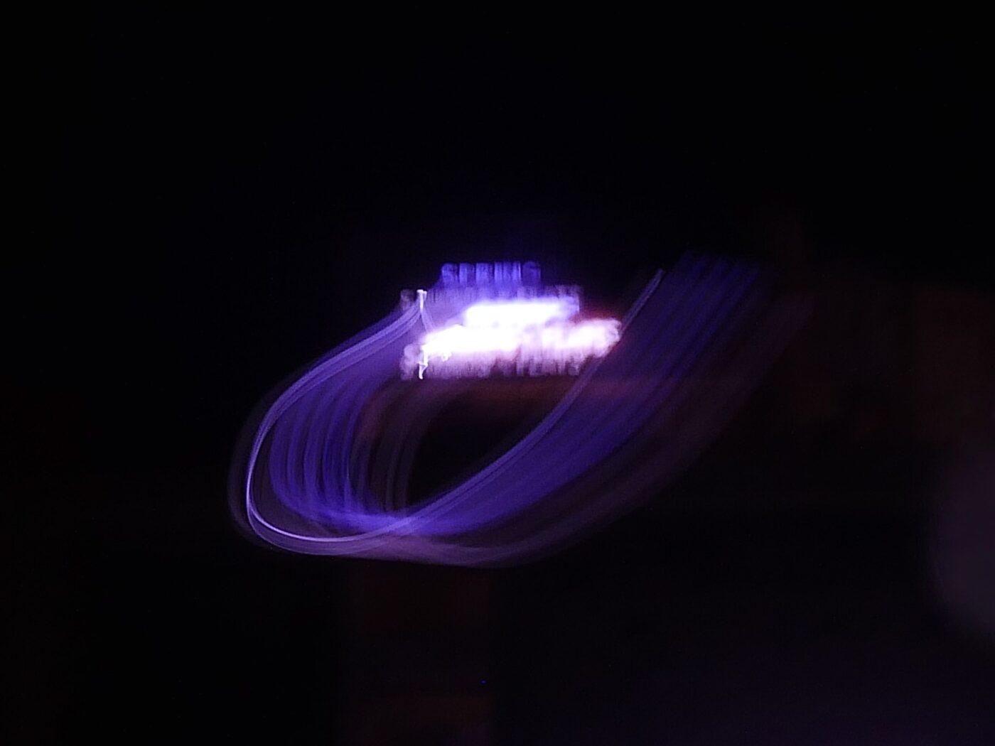 Abstract photo with purple neon light trails on a black background.- nbcreations