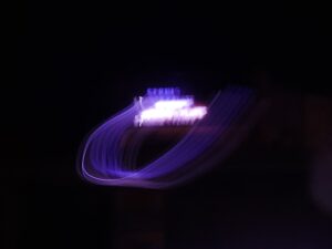 Abstract photo with purple neon light trails on a black background.- nbcreations