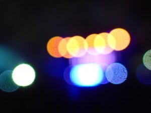 Abstract bokeh lights with blue, orange, and green circles on a black background.- nbcreations