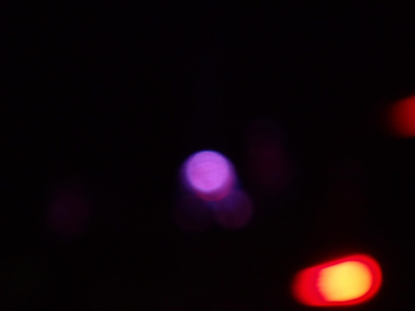 Abstract photo with purple and red blurry lights on a black background.- nbcreations