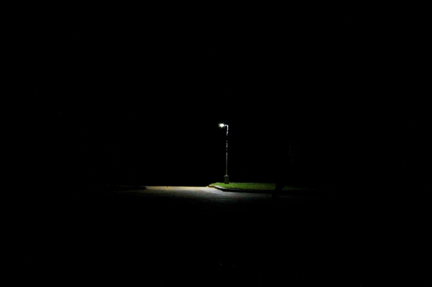 Lit streetlamp surrounded by darkness at night – solitary urban light - nbcreations