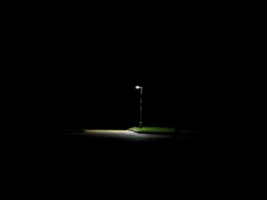Lit streetlamp surrounded by darkness at night – solitary urban light - nbcreations