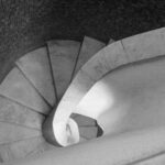 Spiral marble staircase seen from above, with a tiled wall and soft lighting – nbcreations