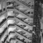Rows of escalators crossing multiple levels in a large modern shopping mall, in black and white – nbcreations